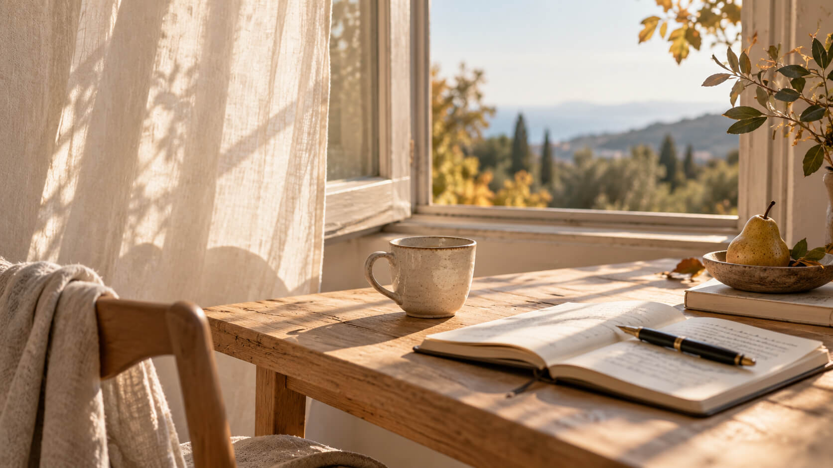 Mesa de madera junto a una ventana abierta, con una taza, un cuaderno y una pera iluminados por la luz cálida de comienzos de otoño.